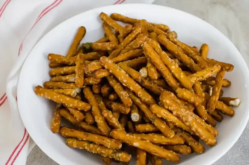 imagen de pretzels sazonados en freidora en un bol blanco y una servilleta blanca con rayas rojas a la derecha del bol